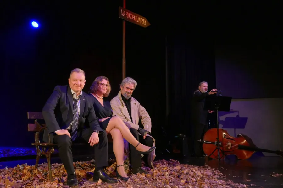 Zdjęcie przedstawia trzy osoby siedzące na ławce na scenie teatralnej. Jedną z nich jest Dariusz Bereski, aktor. Dwie pozostałe Dyrektor MDK w Radomsku oraz pracownica tego ośrodka.