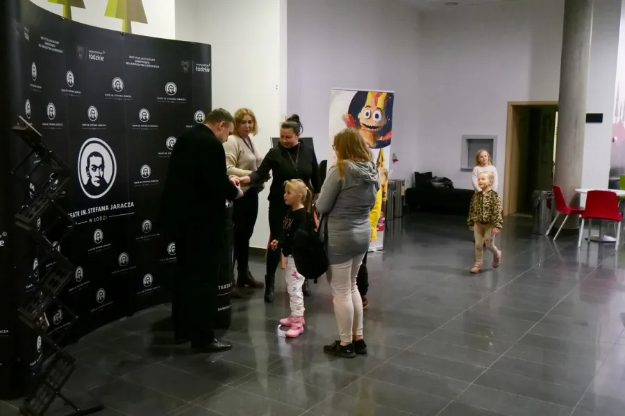 zdjęcie przedstawia widzów oczekujących na wejście na salę teatralną, na foyer w Miejskim Centrum Kultury w Bełchatowie