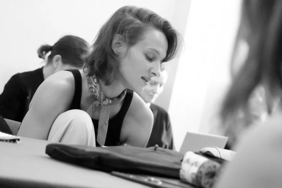 pierwsza próba spektaklu „Czas na wielki numer", na zdjęciu aktorka Natalia Klepacka, któa siedzi przy stole, z jedną nogą podciągniętą do klatki piersiowej, czyta egzemplarz,fot. Marcin Nowak