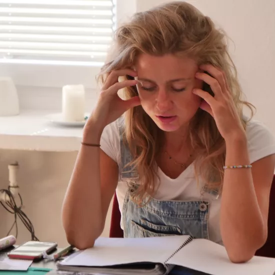 Zdjęcie przedstawia próbę stolikową do spektaklu „Ifigenia ze Splott”. Z łokciami na stole siedzi intensywnie myśląca Agnieszka Skrzypczak. Palce obydwu dłoni aktorki dotykają jej skroni. Jej oczy są zamknięte a usta lekko otwarte. Na stole, nad którym pochyla się aktorka znajduje się zeszyt, długopis, telefon, kubek w kwiaty i czarno-białe zdjęcia.