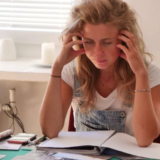 Zdjęcie przedstawia próbę stolikową do spektaklu „Ifigenia ze Splott”. Z łokciami na stole siedzi intensywnie myśląca Agnieszka Skrzypczak. Palce obydwu dłoni aktorki dotykają jej skroni. Jej oczy są skierowane poniżej obiektywu na fotografie a usta są lekko otwarte. Na stole, nad którym pochyla się aktorka znajduje się zeszyt, długopis, telefon, kubek w kwiaty i czarno-białe zdjęcia.