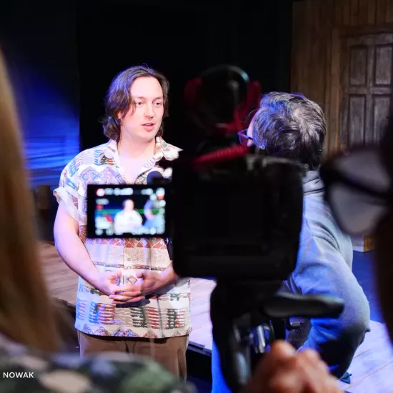 Zdjęcie z próby medialnej spektaklu „Zamiana". Na zdjęciu w nieostrości widać aktora Konrada Krupińskiego, który jest widoczny na podglądzie kamery. 