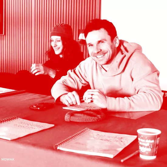 Zdjęcie przedstawia pierwszą próbę spektaklu „Morderstwo w hotelu”. Na zdjęciu widać dwójkę aktorów Natalię Klepacką, która jest oparta na krześle i się śmieje oraz Krzysztofa Wacha, który śmiejąc się patrzy prosto w obiektyw aparatu. Na zdjęcie został nałożony czerwony filtr.