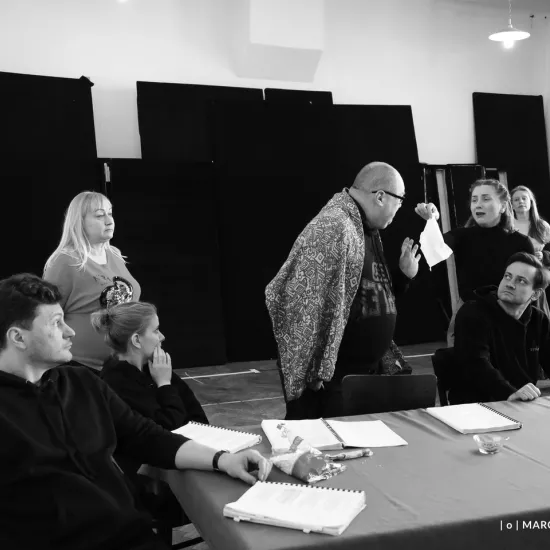 zdjęcie przedstawia próbę spektaklu „Świętoszek"  w reżyserii Magdaleny Piekorz, na zdjęciu Marcin Włodarski,który siedzi przy stole, inspicjentka Katarzyna Brudek stojąca obok stołu, siedząca przy stole Sara Lityńska. Przy stole stoi Paweł Tucholski z serwetką w ręku, na krześle zwrócony w jego stronę siedzi Marek Nędza. Na przeciwko Pawła Tucholskiego stoi Iwona Dróżdż, w tle Matylda Paszczenko. Autorem zdjęcia jest Marcin Nowak