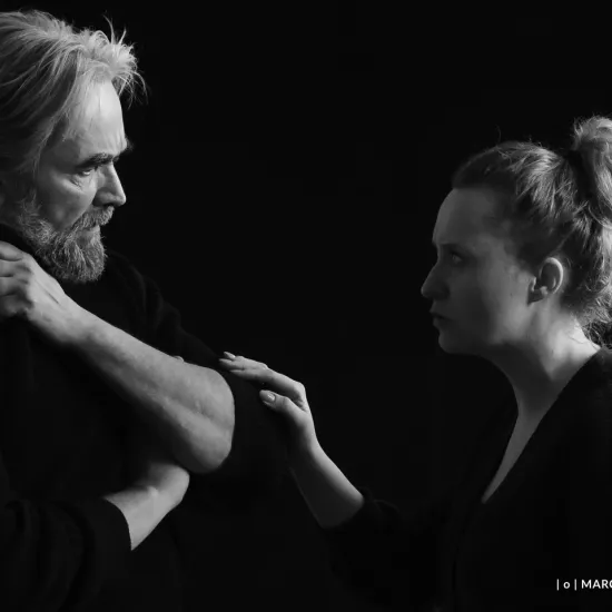 zdjęcie przedstawia próbę spektaklu „Świętoszek" w reżyserii Magdaleny Piekorz. Na zdjęciu jest dwójka aktorów w planie amerykańskim, stoją naprzeciwko siebie: po lewej stronie Dariusz Bereski, którego lewa ręka jest na klatce piersiowej i dotyka prawego obojczyka, a prawa ją podbiera na dole. Na przeciwko stoi aktorka Iwona Karlicka, która prawą ręką dotyka łokcia Dariusza Bereskiego. 