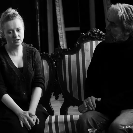 zdjęcie przedstawia próbę spektaklu „Świętoszek" w reżyserii Magdaleny Piekorz. Na zdjęciu dwoje aktorów, którzy siedzą na kanapie. Po lewej stronie Iwona Karlicka, po prawej Dariusz Bereski. 