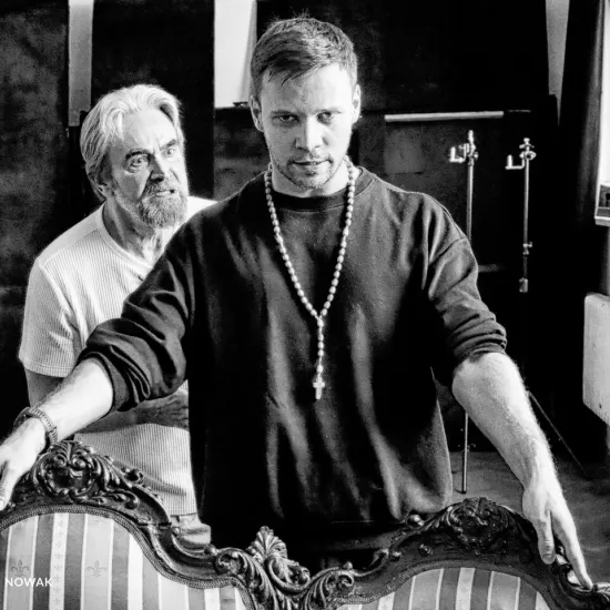 próba do spektaklu „Świętoszek", na zdjęciu: Dariusz Bereski stojący w tle i Łukasz Stawowczyk opierający się o kanapę, fot. Marcin Nowak. Zdjęcie jest czarno-białe