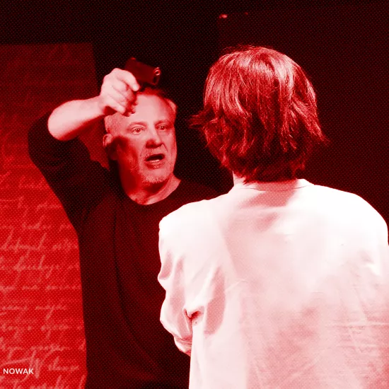 próba spektaklu „Morderstwo w hotelu", na zdjęciu Mariusz Witkowski celujący z pistoletu w Natalię Klepacką, fot. Macin Nowak. Na zdjęcie został nałożony czerwony filtr.