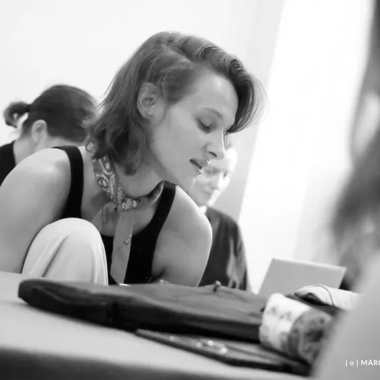 pierwsza próba spektaklu „Czas na wielki numer", na zdjęciu aktorka Natalia Klepacka, któa siedzi przy stole, z jedną nogą podciągniętą do klatki piersiowej, czyta egzemplarz,fot. Marcin Nowak