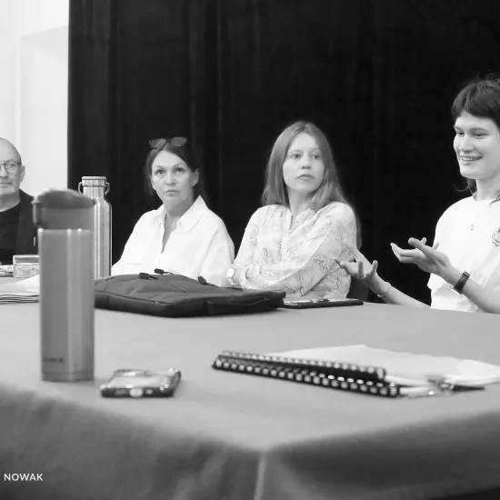 pierwsza próba spektaklu „Czas na wielki numer", na zdjęciu od lewej przy stole siedzą: dyrektor Paweł Łysak, aktorka Monika Badowska, aktorka Matylda Paszczenko, reżyserka Barbara Bendyk, która gestykuluje opowiadając o spektaklu, na zdjęcie nałożony jest czarno-biały filtr, fot. Marcin Nowak 