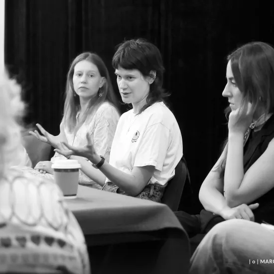 pierwsza próba spektaklu „Czas na wielki numer", na zdjęciu siedzące przy stole od lewej aktorka Matylda Paszczenko, reżyserka Barbara Bendyk, która gestykuluje oraz scenografkę Wiktorię Kubat. Na zdjęcie nałożony jest czarno-biały filtr, fot. Marcin Nowak 